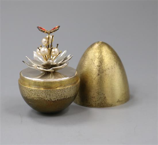 A silver-gilt surprise egg by Stuart Devlin, opening to reveal an enamelled butterfly resting on a silver flower